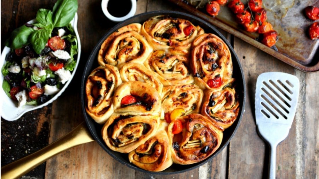 Pizza Twister on wooden chopping board with roast cherry tomatoes and spatula