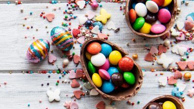 Colourful sweets inside chocolate easter egg on white background