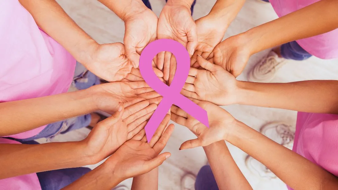 women's hands holding a pink ribbon